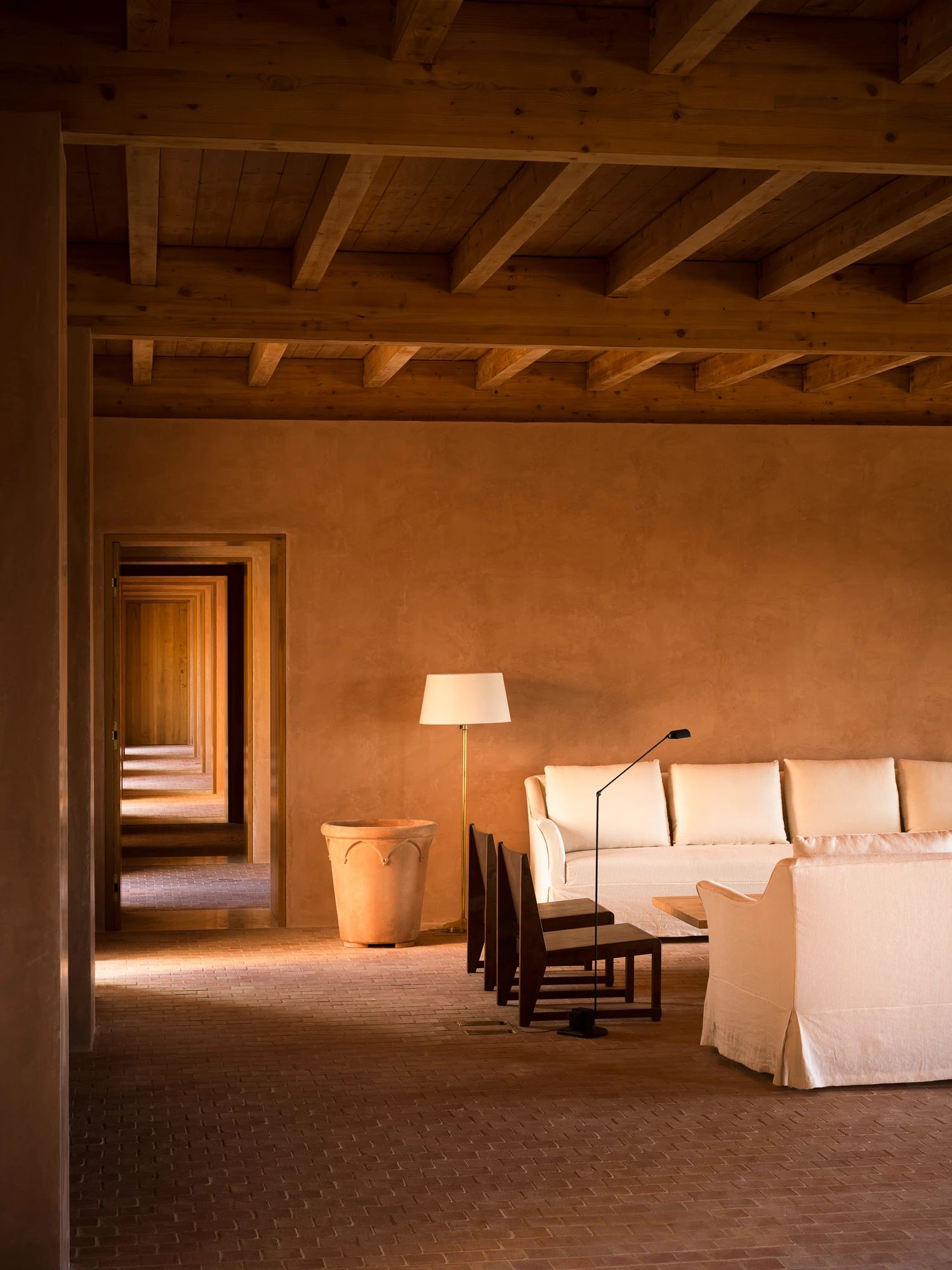 The lounge, seen through an enfilade of doorways under a timber-beamed ceiling.