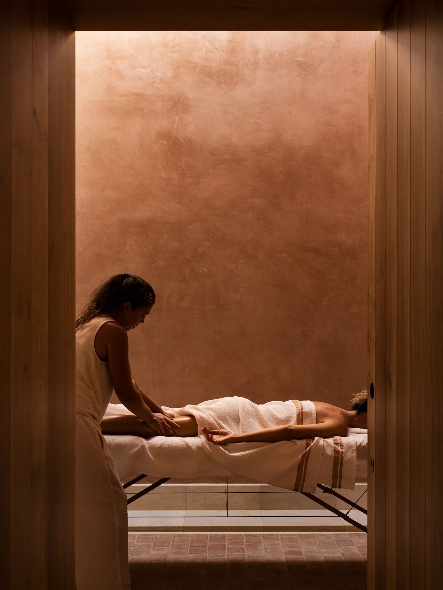 A therapy session in progress, seen through a doorway into a rammed-earth room.