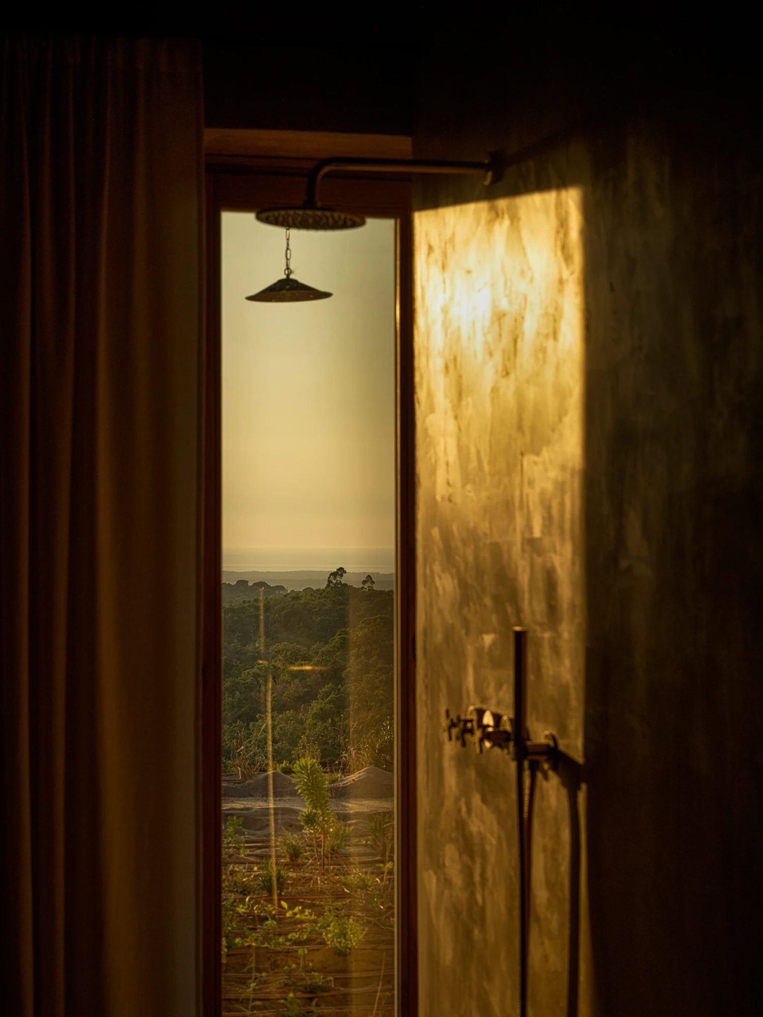 A shower open to the landscape, with the valley visible through the doorway.