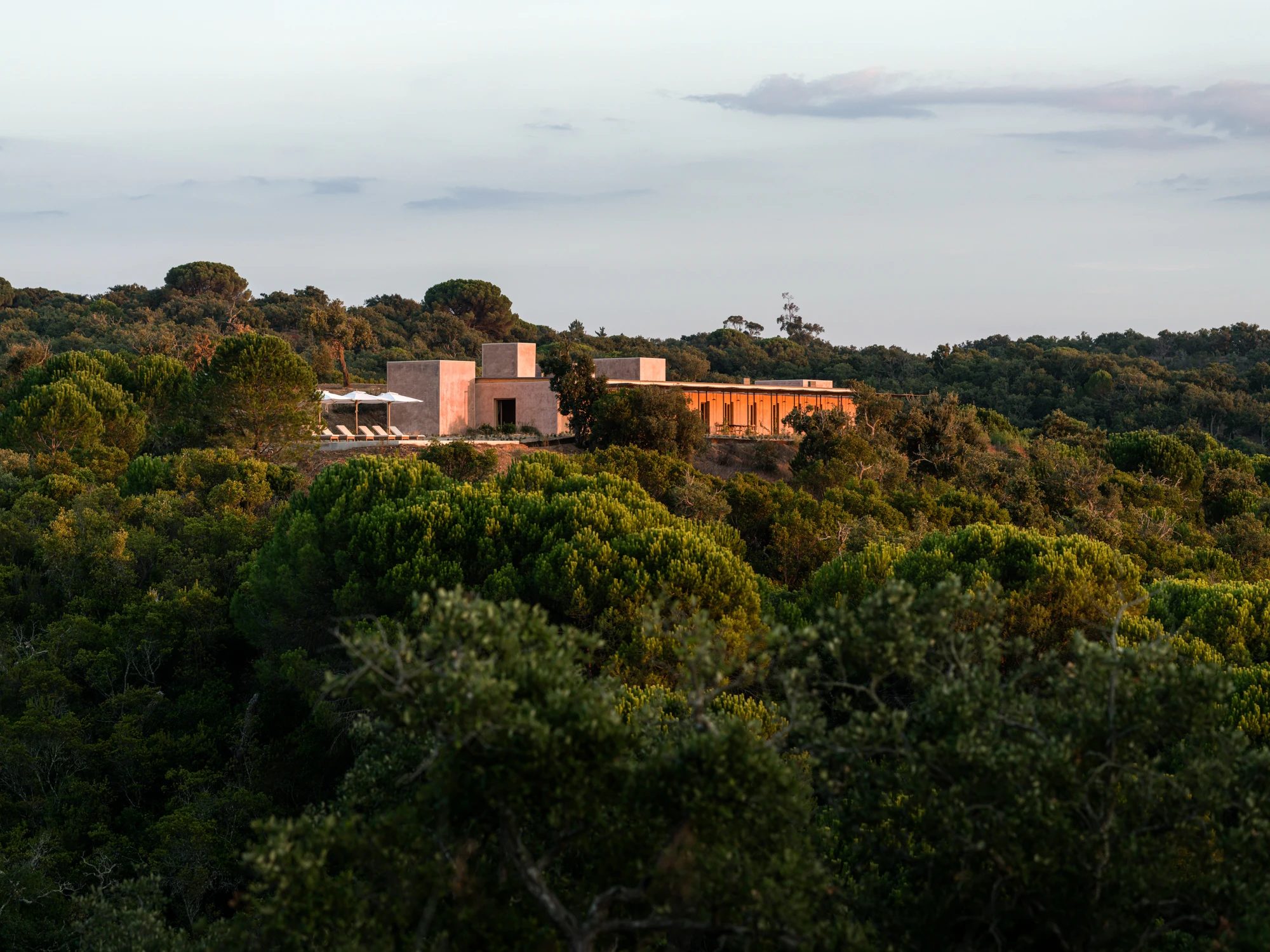 The house at dusk, low on the hillside among the cork oak forest.