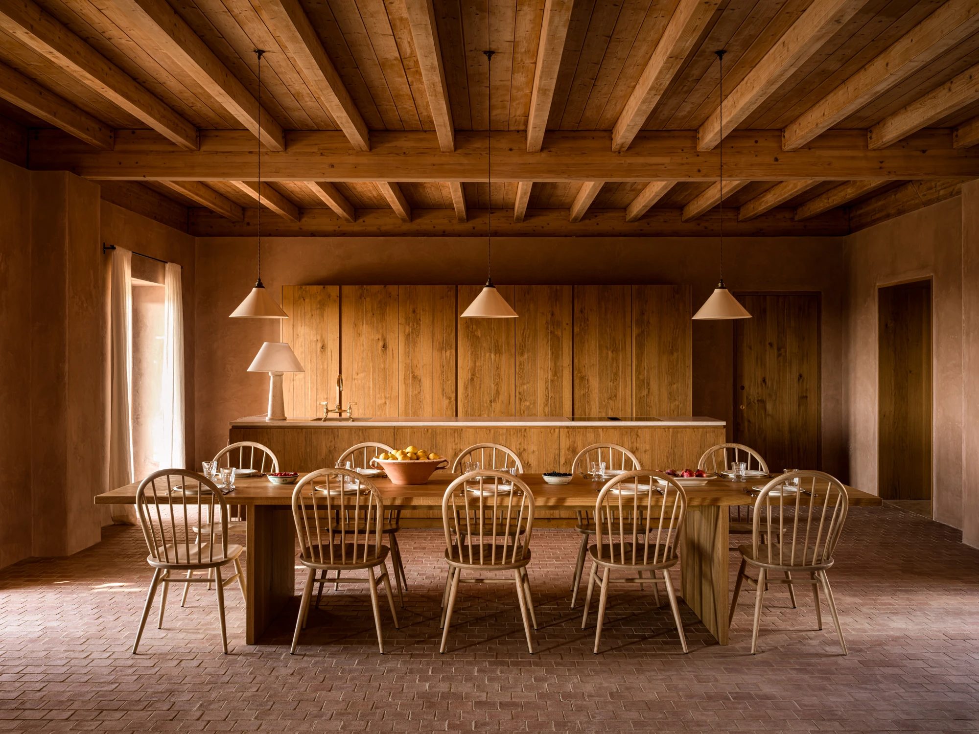 The dining room: a long table with spindle chairs beneath conical pendant lights.