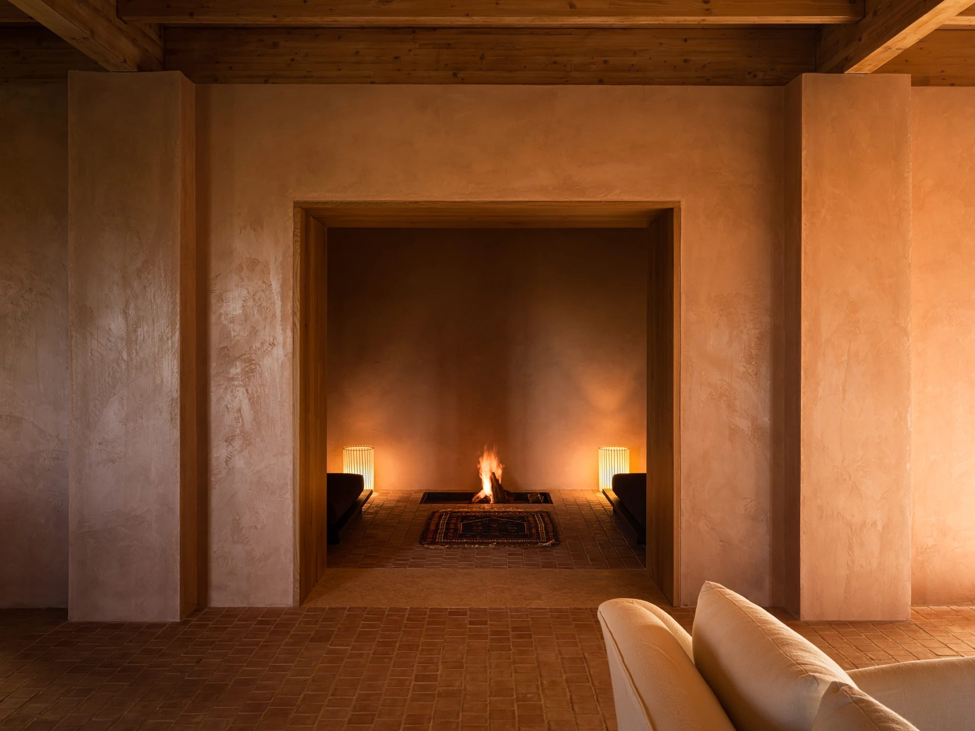 The fireplace lounge, with a fire lit in a deep alcove and candles alongside.